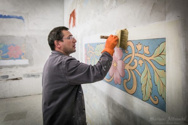 The technician applies glue on the fresco after the plaster has dried