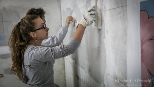 A young artist specialised in the fresco technique prepares the plaster support on which to execute the work