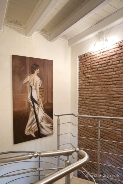 The Black Sash, a work by Boldini frescoed by Mariani. The classic fresco painting, antique wall with exposed bricks and stainless steel railing blend beautifully in this stairwell